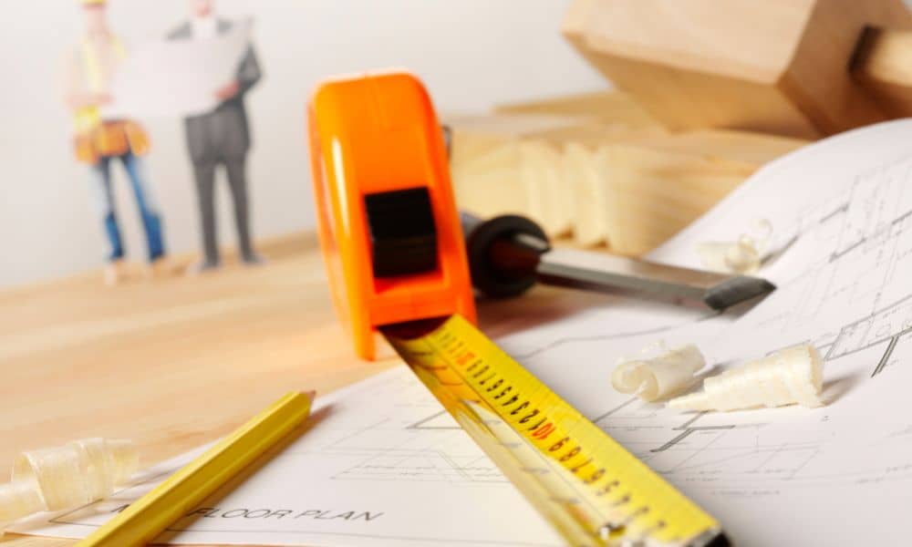 Measuring tape and construction plans showing the detailed work involved in ALTA land title surveys that take weeks to complete