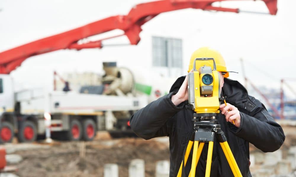 Surveyor using total station for boundary surveys at a construction site
