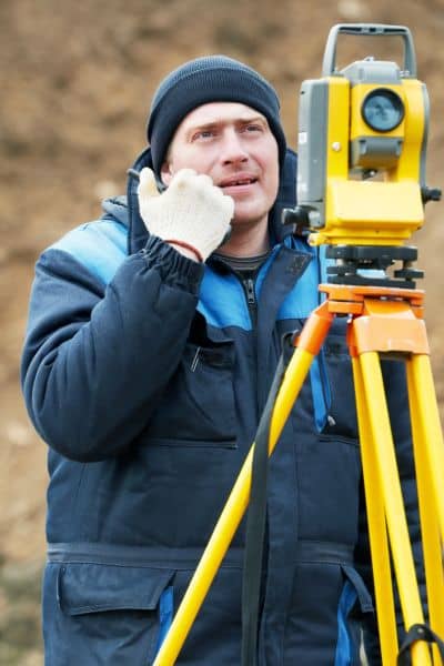 Certified flood surveyor using equipment to verify property elevation for FEMA compliance and local building codes
