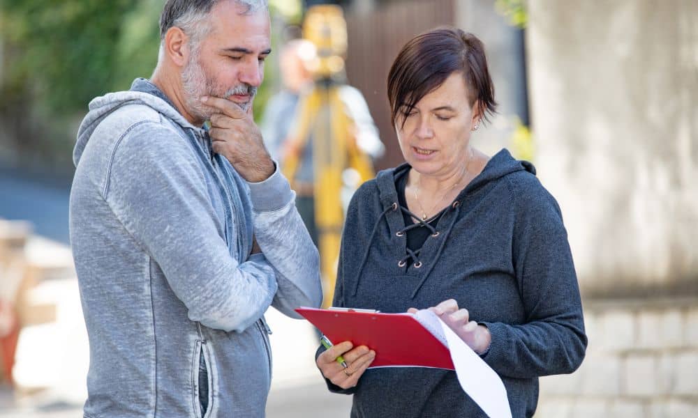 Homeowner and surveyor reviewing property documents during a due diligence survey for insurance verification