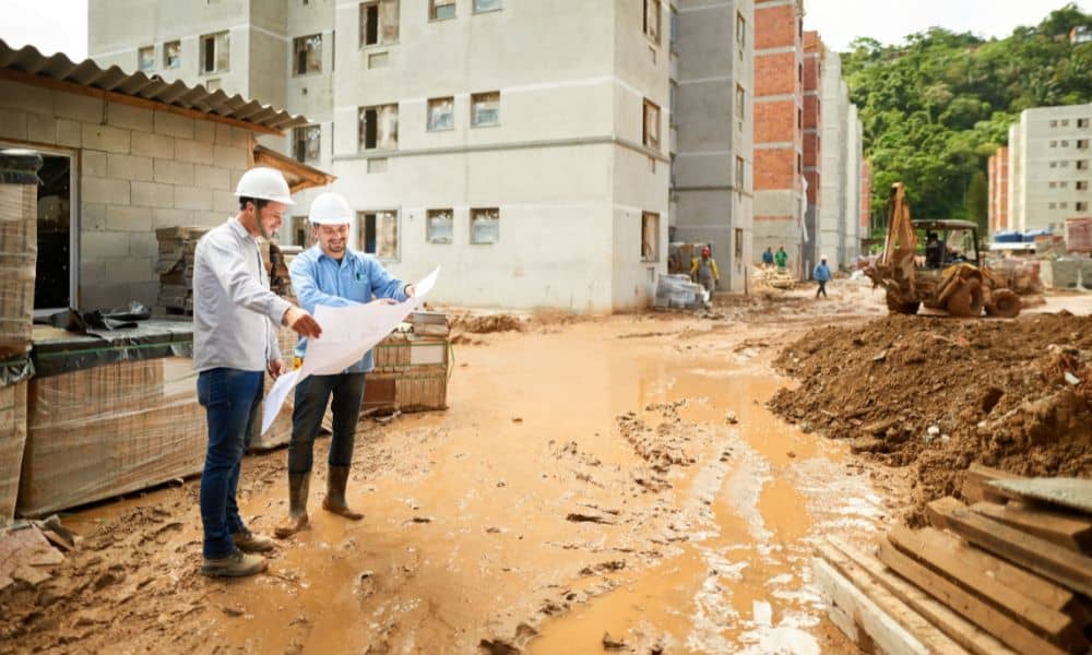 Engineers reviewing site plans for a loan closing survey on an active residential construction site