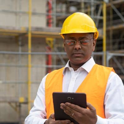 A licensed land surveyor reviewing plans on a tablet as part of a professional boundary survey