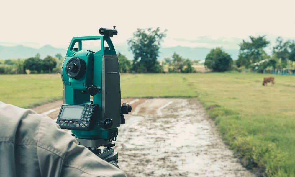 A licensed land surveyor using a total station in the field performing a boundary survey