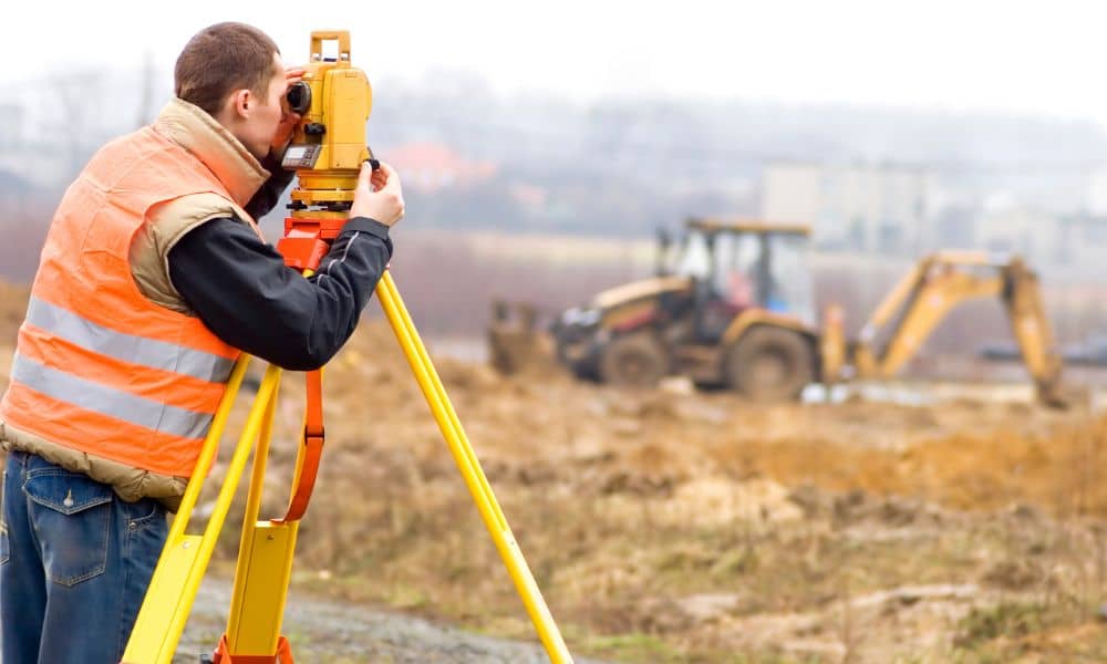 Land surveyor conducting a topographic survey on a cleared construction site before rebuilding