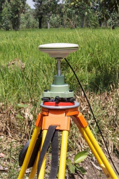 Surveying equipment on a tripod in a grassy area measuring property lines