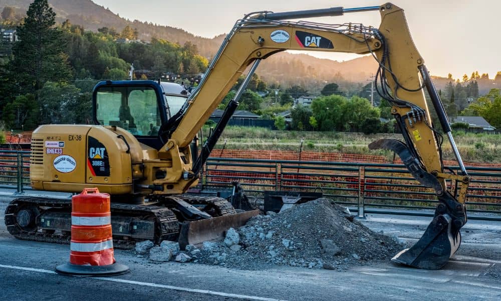 Excavator working on a highway slope repair as part of construction survey planning